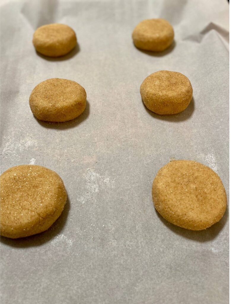 Crumbl Snickerdoodle Cupcake Cookie dough balls flatten on parchment paper