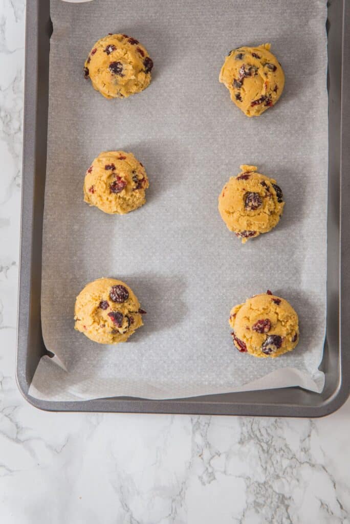 Cranberry Orange Cookie dough balls in baking sheet with parchment paper