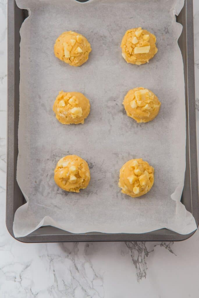 White Chocolate Chip Cookies dough balls on parchment paper and baking sheet