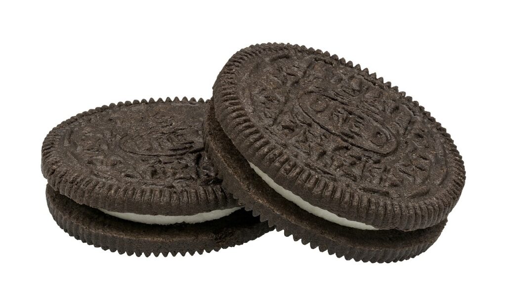 Two classic Oreo sandwich cookies, chocolate wafers with white creme filling, one leaning on the other, on a plain white background.